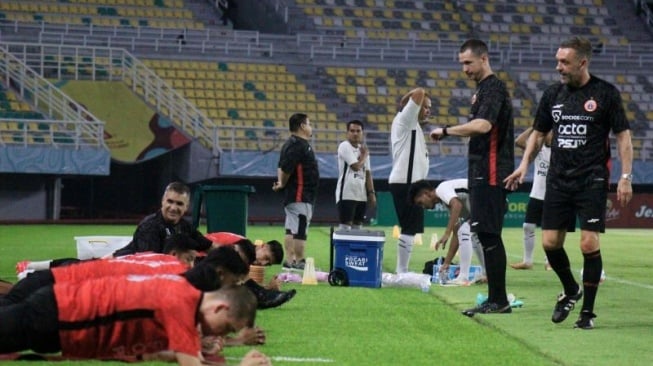 Pelatih Persija Jakarta Thomas Doll (kanan) memberi instruksi kepada para pemainnya saat melakukan peregangan otot dalam sesi latihan ofisial di Stadion GBT Surabaya, Jumat (8/12/2023). (ANTARA/Naufal Ammar Imaduddin)