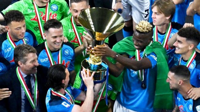 Penyerang Napoli asal Nigeria Victor Osimhen memegang trofi Liga Italia saat ia dan rekan satu timnya merayakan Scudetto musim ini usai laga pekan ke-38 atau terakhir Serie A 2022-2023 kontra Sampdoria pada 4 Juni 2023 di stadion Diego-Maradona di Naples.Tiziana FABI/AFP.